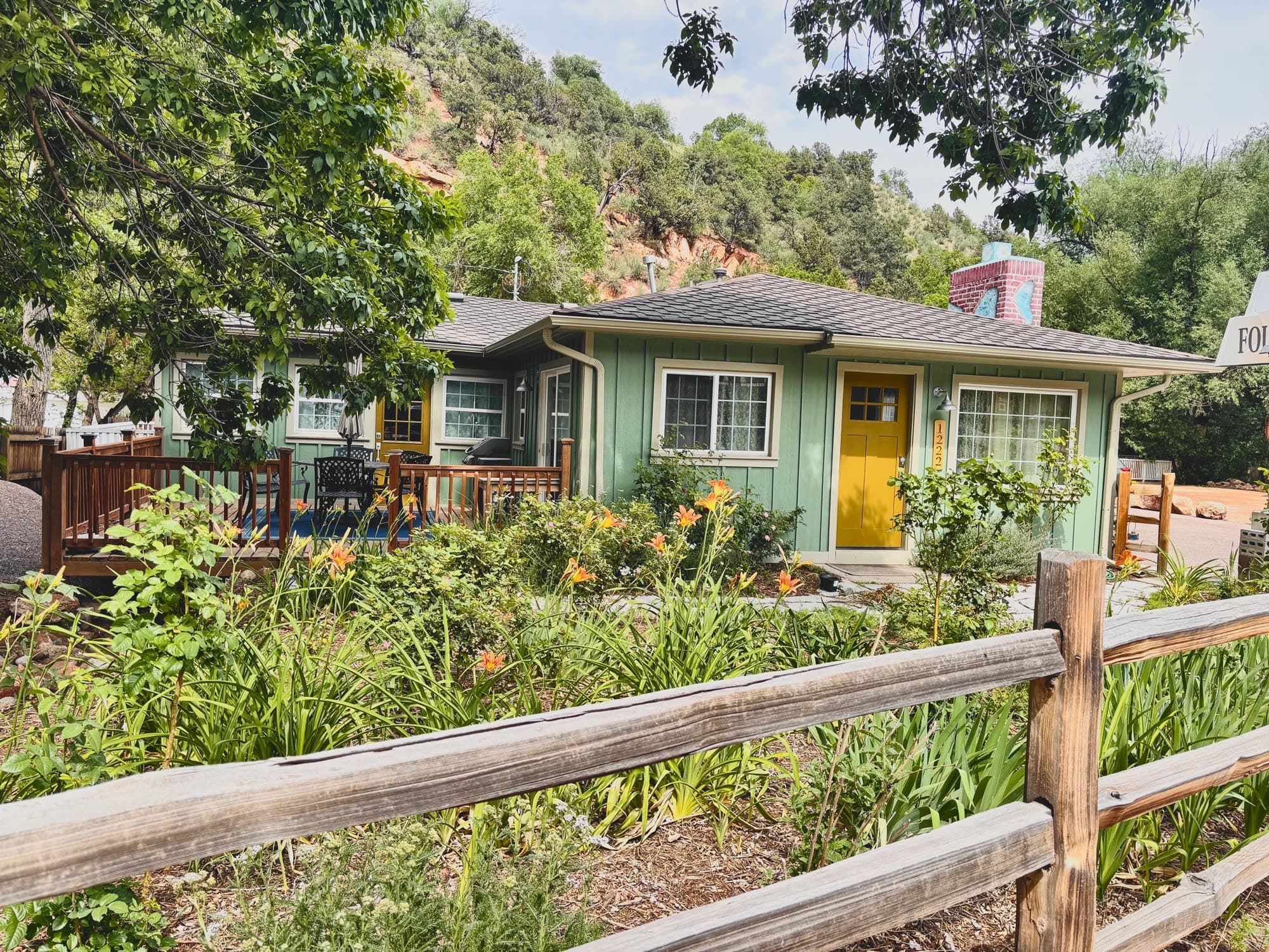 The inn's green cottage with a flower garden and split-rail fence, red rock rising behind